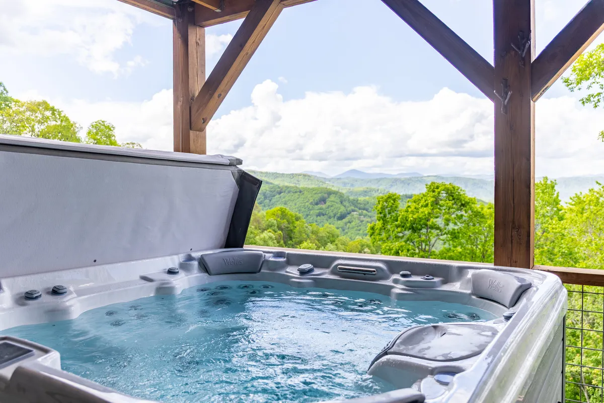 This image features a private hot tub set against a backdrop of stunning mountain views. A wooden structure offers a sense of privacy while allowing guests to enjoy the open air, and the serene ambiance suggests both daytime relaxation and the opportunity for starlit evenings.